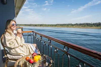 a woman sitting on a boat on the water at live Nile in style Nile cruise in Luxor and Aswan in Luxor