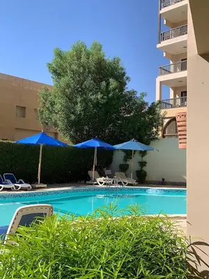 a swimming pool with blue umbrellas and chairs at Private Room Hurghada for rent beach and pools included Not Valid for Locals in Hurghada