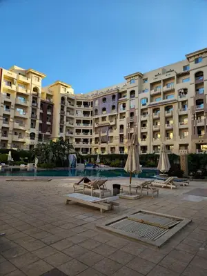 a large building with chairs and umbrellas in a courtyard at Florenza Khamsin Apartments in Hurghada