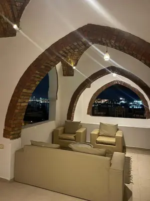 a living room with two chairs and a brick archway at Luxor Palm Villa in Luxor