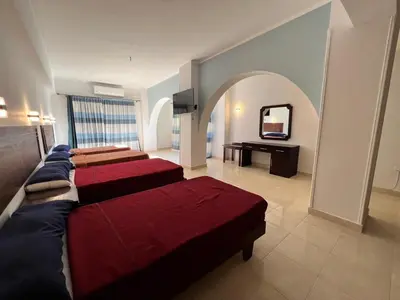 a room with three beds and a television in it at Sea Life Hurghada Apartments in Hurghada