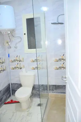 a bathroom with a toilet and a glass shower at Luxe Apartment Inside Karma Beach Resort Al Ahiaa-Beach Free Access in Hurghada