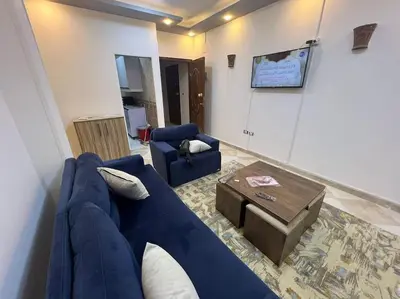 a living room with a blue couch and a table at Spacious 2-Bedroom Apartment - Families Only in Hurghada