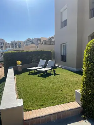 two benches sitting on top of a yard with grass at El-Gouna Water-Side Apartment in Hurghada