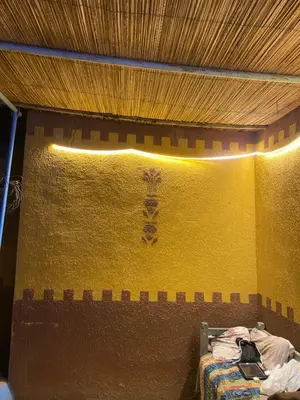a bed in a room with a yellow wall at Bafana Bafana Nubian Hostel in Najâ€˜ al MadÄbb