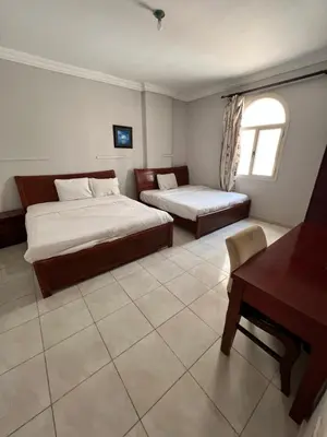 a bedroom with two beds and a table and a desk at H&H Dream in Hurghada