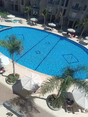 an overhead view of a swimming pool with umbrellas and palm trees at Princess resort flat no217 in Hurghada