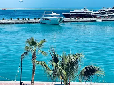 two boats are docked in a harbor with palm trees at Marina Suite in Hurghada