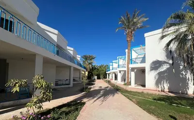 a building with palm trees next to a sidewalk at Elegant 2-Bedroom Suite Mirage Bay in Hurghada