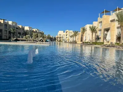 a large pool of water with buildings and palm trees at Mangroovy- 1BR Sparkling Condo in Hurghada