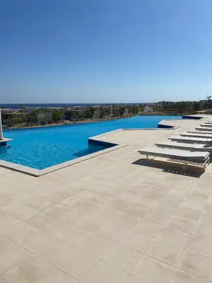 a swimming pool with a row of chaise lounge chairs at Luxury One Bedroom Apartment with Sea view in SomaBay in Hurghada