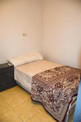 a small bedroom with a bed and a dresser at Pauline Guest House in Luxor