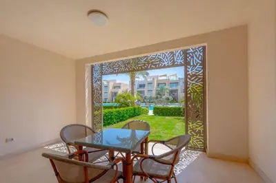 a dining room with a glass table and chairs and a door at Stylish Gouna Escape 2BR Mangroovy Beach Pool Access in Hurghada
