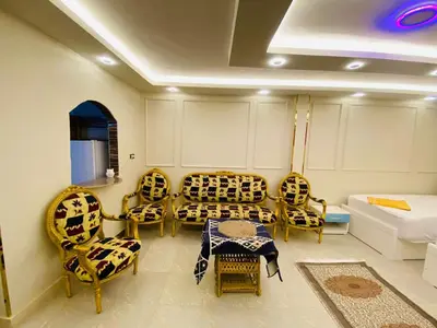 a living room with chairs and a table and a bed at Basmatic2 Nubian Guest House in Aswan