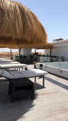 a patio with two tables and a straw umbrella at Imperial resort in Hurghada