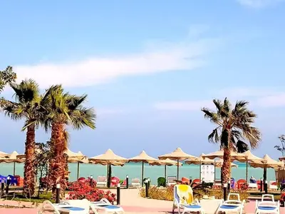 a beach with palm trees and chairs and umbrellas at Casablanca Beach hurgada كازابلانكا بيتش الغردقه in Hurghada