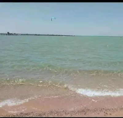a beach with the ocean and a pier in the background at بالما ريزورت in Hurghada