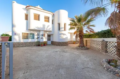 a white house with palm trees in front of it at Aden Beach - Sea View room with beach access in Villa in Hurghada