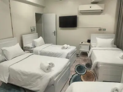 a hospital room with three beds and a television at Aswan Key Cozy in Nag` el-Ramla