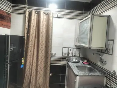 a small kitchen with a sink and a shower at Aswan Key Cozy in Nag` el-Ramla