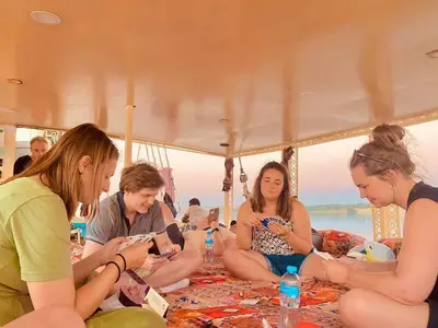a group of people sitting around a table looking at their cell phones at Felucca sailing boat from Aswan to komombo with private bathroom in Aswan