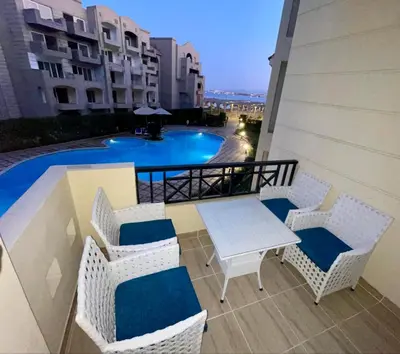 a balcony with a table and chairs and a pool at Sahl Hasheesh, El Andalous by sea and pool view, private beach in Hurghada