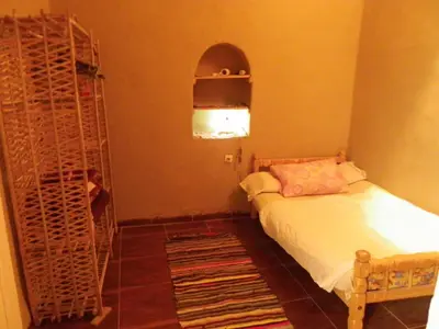 a small bedroom with a bed and a shelf at maison luxor in Al Aqālitah
