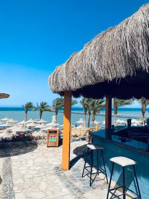a bar on the beach with chairs and umbrellas at Apartment in el karma aqua beach resort hurghada near el gouna 2 in Hurghada