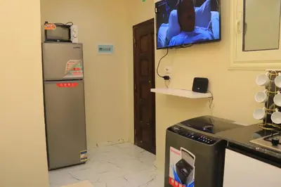 a kitchen with a refrigerator and a tv on the wall at Hossam Apartment Marina Area Hurghada in Hurghada
