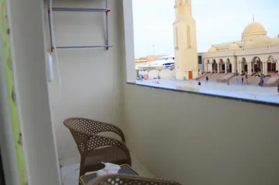 a cat sitting in a chair looking out a window at a mosque at Hossam Apartment Marina Area Hurghada in Hurghada
