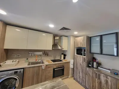 a kitchen with wooden cabinets and a washer at Mangroovy Serinity 2br pool view in Hurghada