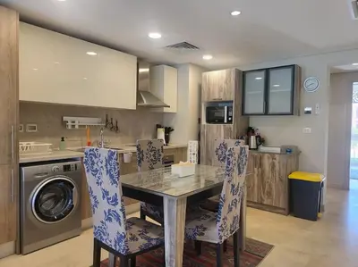 a kitchen with a table and chairs and a dishwasher at Mangroovy Serinity 2br pool view in Hurghada