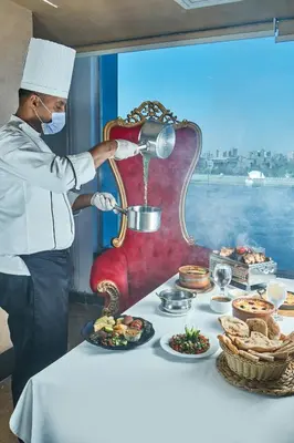 a man in a chefs hat preparing food on a table at Al Fanar Azur Hotel in Suwhaj