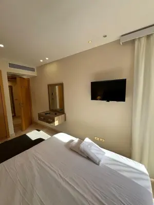 a bedroom with a white bed and a flat screen tv at Scarab El Gouna in Hurghada