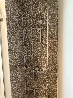 a shower in a bathroom with a stone wall at Penthouse 3 Bedrooms in Swan Lake ElGouna in Hurghada