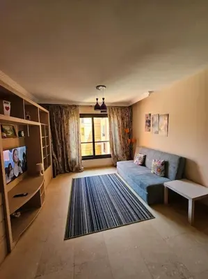 a living room with a blue couch and a large window at Esplanada flat with free beach, no single men in Hurghada