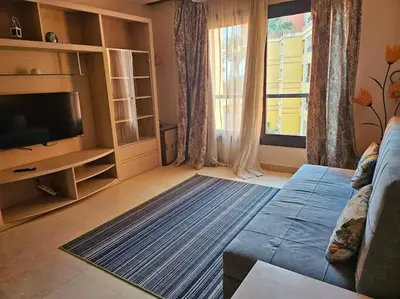 a living room with a blue couch and a television at Esplanada flat with free beach, no single men in Hurghada