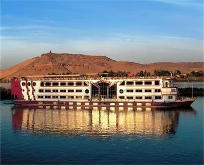 a large boat in the water with a mountain in the background at Sofia Nile Cruise Luxor & Aswan in Luxor