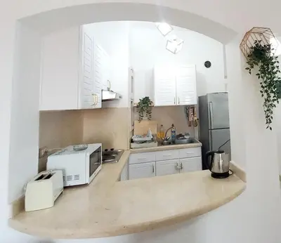 a kitchen with white cabinets and a microwave at Westgolf y 62 1-8 in Hurghada