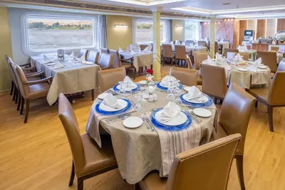 a dining room with tables and chairs and a large window at Nile Cruise 3 Nights Aswan to Luxor Sightseeing Included in Nag` el-Ramla
