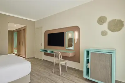 a room with a bed and a tv and a chair at Doubletree By Hilton Mangroovy El Gouna Resort in Hurghada