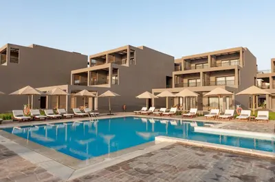 a swimming pool with chairs and umbrellas in front of a building at Sentido Naga Bay - Adults friendly in Hurghada