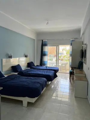 a bedroom with three beds and a television in it at Sea Life Apartments-hotel in Hurghada