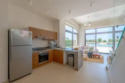 a kitchen with a stainless steel refrigerator and a living room at The Lakefront Villa 4BR at Cyan ElGouna in Hurghada