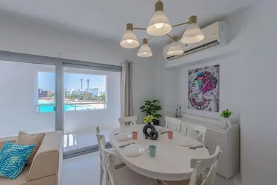 a white dining room with a white table and chairs at Elegant 3BR on Swan Lake Crystal Lagoon at Elgouna Families Only in Hurghada