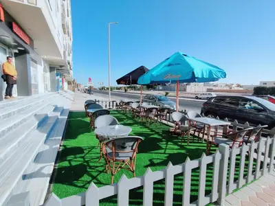 a row of tables and chairs with an umbrella on a sidewalk at جوليانا بيتش ريزورت in Hurghada