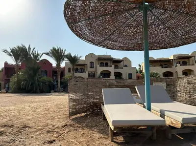 two lounge chairs and an umbrella on a beach at Cozy Townhouse in West Golf - El Gouna in Hurghada