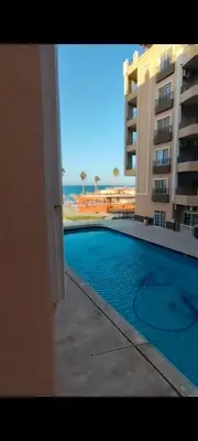 a swimming pool with a view of a building and the ocean at Juliana beach in Hurghada