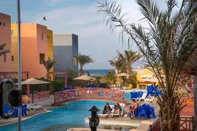 a pool at a resort with people sitting on chairs and a bridge at Al Dora Resort All Inclusive Hotel in Hurghada