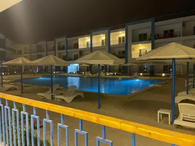 a swimming pool with chairs and umbrellas in front of a building at قرية ميراج باي in Hurghada